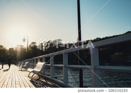 White Old wood bridge pier against beautiful sunset sky natural background, backdrop wallpaper multipurpose sea scene. White benches no people in Gdynia Orlowo, Poland. Wooden pier, molo with marina 106310285