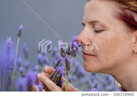 Aromatherapy, cute young womanenjoys the smell of lavender flowers while walking outdoor 106310908