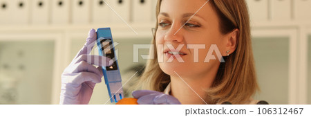 The woman in laboratory checks the orange citrus dosimet 106312467