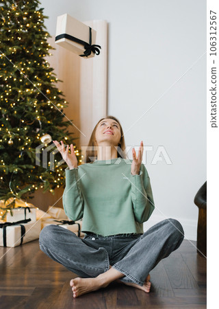 Young happy woman in homemade clothes throws a Christmas gift box up and has fun Young happy woman in homemade clothes throws a Christmas gift box up and has fun 106312567