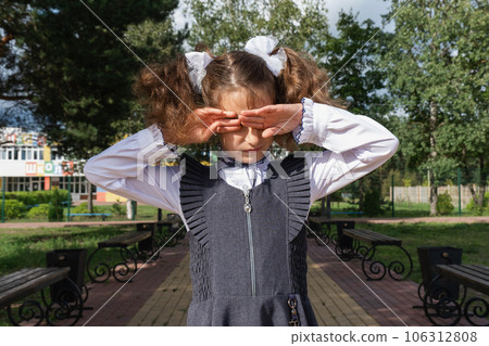 Girl with a backpack near the school after classes, unhappy, tired and headache. The child is crying, holding his head in his hands. Academic failures, poor grades, overwork Girl with a backpack near the school after classes, unhappy, tired and headache. The child is crying, holding his head in his hands. Academic failures, poor grades, overwork 106312808