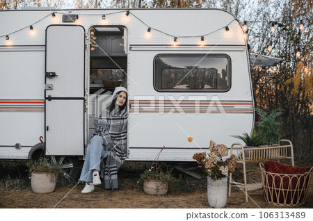 Caucasian woman sits in a van on a warm autumn day. Travel in a camper. 106313489