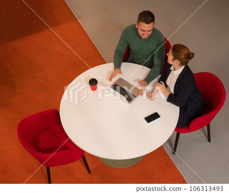 Top view of man and woman working on laptop at round table. Top view of man and woman working on laptop at round table. 106313493
