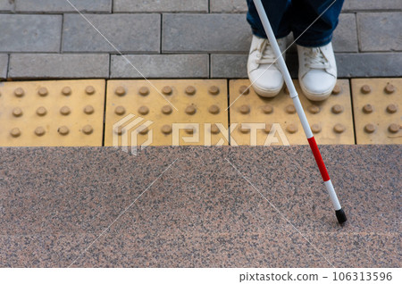 Close-up of female foot, walking stick and tactile tiles. 106313596