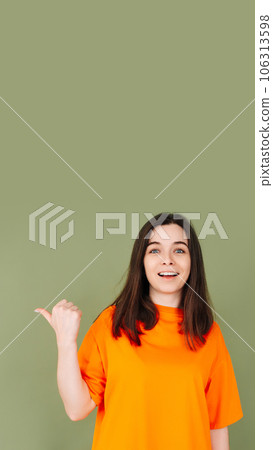 Cheerful lady in stylish orange clothing points to empty advertising space. Perfect for affordable Cheerful lady in stylish orange clothing points to empty advertising space. Perfect for affordable 106313598