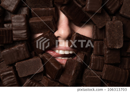 The face of a caucasian woman surrounded by chocolates. girl showing tongue.  106313703