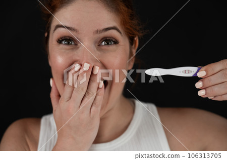 Portrait of happy caucasian woman holding positive express pregnancy test on black background.  106313705