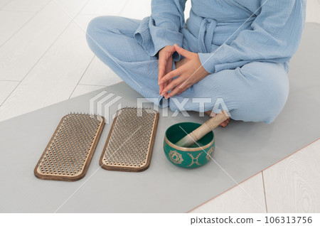 Asian woman sitting on yoga mat with tibetan singing bowl and sadhu boards. Asian woman sitting on yoga mat with tibetan singing bowl and sadhu boards. 106313756