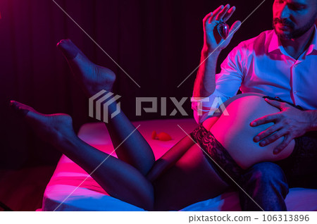 A man with a mistress on his knees holds an anal plug in the bedroom. 106313896