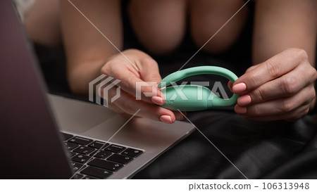 A woman lies on the bed and synchronizes the kegel machine with a laptop. A woman lies on the bed and synchronizes the kegel machine with a laptop. 106313948