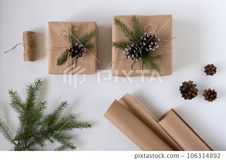 Two gift boxes in craft paper with spruce branches and cones 106314892
