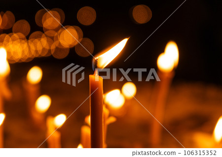 A lot of burning candles in the temple in the dark. The concept of religion, prayer and God. 106315352