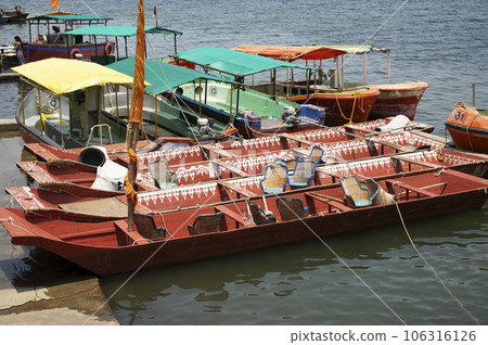 INDIA, MADHYA PRADESH, MAHESHWAR, July 2023, Tourist with colourful boats parked near Maheshwar Ghat, situated on the banks of River Narmada 106316126