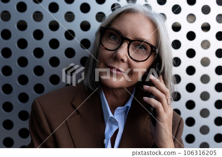 confident 60 year old gray-haired business woman with a bob haircut is dressed in a brown jacket and 106316205