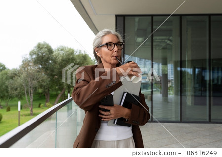 well-groomed elderly gray-haired business woman in a brown jacket and trousers is waiting for a 106316249