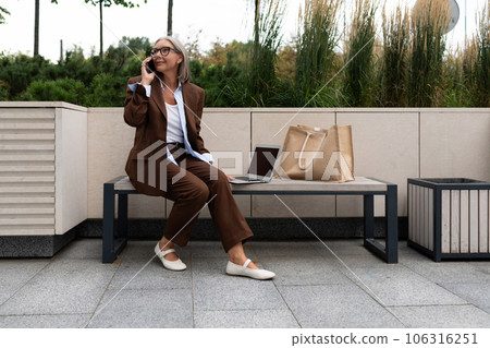 a gray-haired middle-aged woman dressed in a stylish suit is waiting for a business meeting on the 106316251
