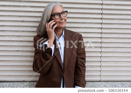 A 60 year old successful Caucasian business lady dressed in a brown stylish suit speaks on a 106316354