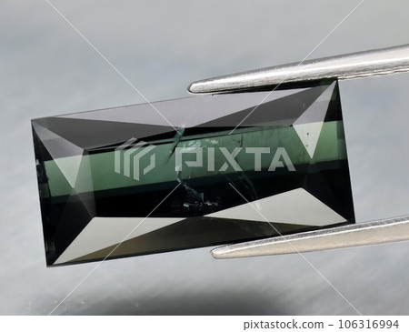 Natural gemstone green tourmaline on gray background Natural gemstone green tourmaline on gray background 106316994
