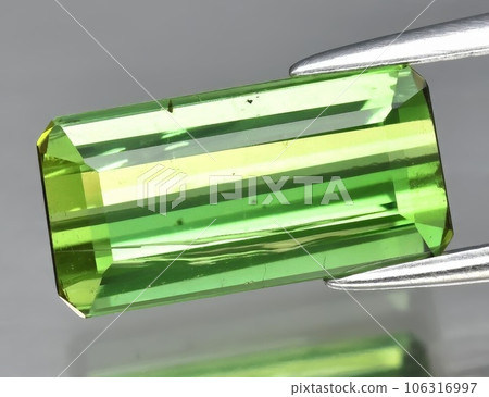 Natural gemstone green tourmaline on gray background Natural gemstone green tourmaline on gray background 106316997