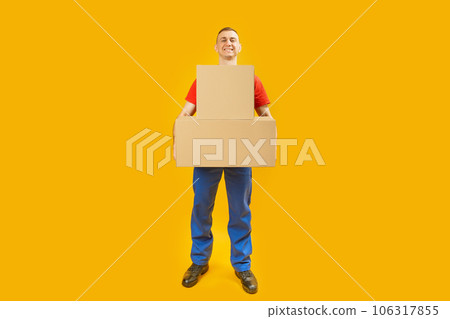 Full-length portrait of young man with large cardboard boxes on yellow background. Copy space, mock up. Full-length portrait of young man with large cardboard boxes on yellow background. Copy space, mock up. 106317855