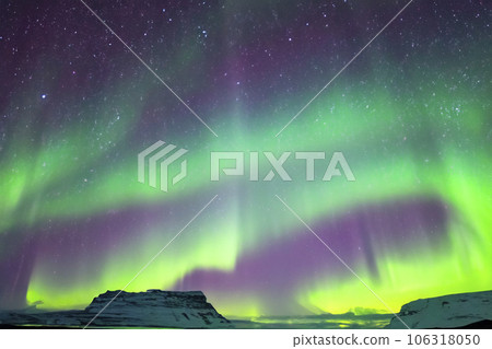 Northern Lights. Aurora. Iceland. Moment of greatest activity. Northern lights over the sea, snowy mountains. Starry sky. Winter landscape with aurora. Tree silhouette. Villages silhouette. 2023. 106318050