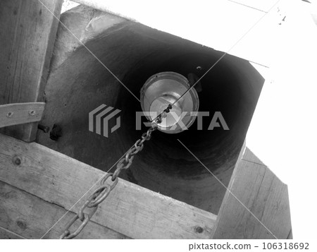 Old well with iron bucket on long forged chain for clean drinking water 106318692