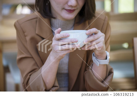 Close up Woman hand holding black coffee cup in green garden cafe. Hands of businesswoman love drinking hot coffee. business women with black coffee or hot chocolate in coffee shop. Caffeine drinking Close up Woman hand holding black coffee cup in green garden cafe. Hands of businesswoman love drinking hot coffee. business women with black coffee or hot chocolate in coffee shop. Caffeine drinking 106319213