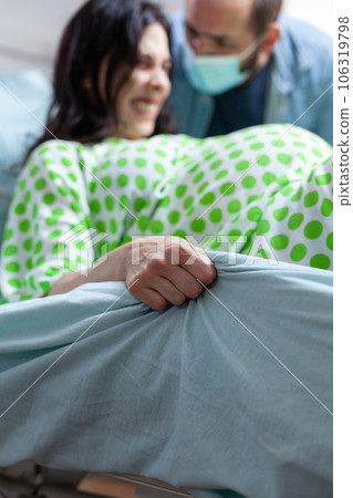Pregnant woman pushing hard to delivery baby in hospital ward, having husband beside her during caesarean surgery. Patient with pregnancy having paniful contractions during childbirth Pregnant woman pushing hard to delivery baby in hospital ward, having husband beside her during caesarean surgery. Patient with pregnancy having paniful contractions during childbirth 106319798