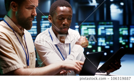 Coworkers overseeing supercomputers helping businesses manage databases, host websites and store files. Technicians auditing server room infrastructure used for high performance computing Coworkers overseeing supercomputers helping businesses manage databases, host websites and store files. Technicians auditing server room infrastructure used for high performance computing 106319887