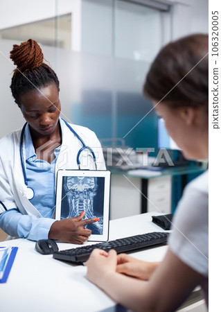 Radiology specialist doctor with x-ray ct scan of cervical injury giving medical result to patient during clinical appointment. Radiologist presenting treatment for soreness, pain, ache symptoms 106320005