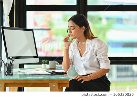 Professional female accountant using calculator to check company finances income and budget at office desk 106320826