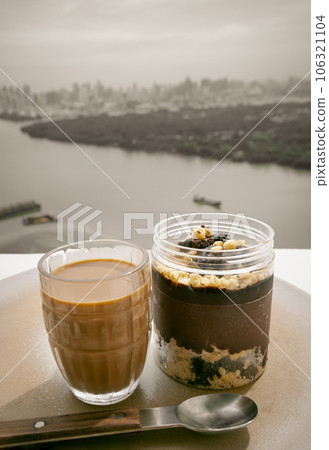 Good morning with Coffee in glass cup and Crumble dark chocolate brownie served and served with spoon with river view. 106321104