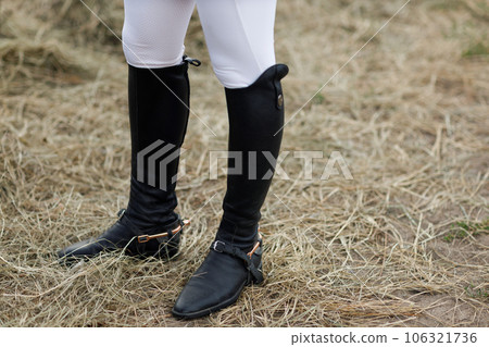 Female legs in black leather boots close up rider jockey standing at stable 106321736