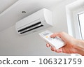 Air conditioner temperature adjustment with remote controller in room at home. Hand holding remote controller of air conditioner inside the white room and set at cool temperature 106321759
