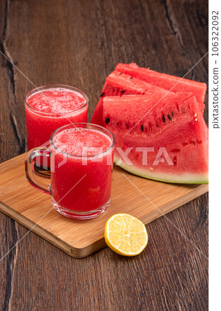Watermelon juice in glass mugs, lemon slice and watermelon slices on a wooden board. Watermelon juice in glass mugs, lemon slice and watermelon slices on a wooden board. 106322092