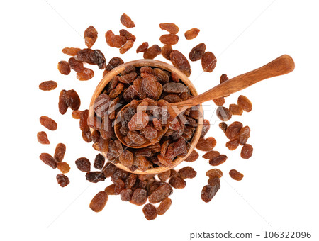 Top view of sweet raisins on a spoon and in a bowl over white background. 106322096