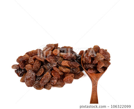 A spoonful of raisins next to a bunch of sweet raisins on a white background. A spoonful of raisins next to a bunch of sweet raisins on a white background. 106322099