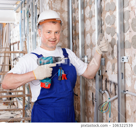 Construction worker using screw gun for aluminum profile mounting at indoors building site 106322539