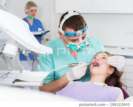 Male dentist performing treatment to girl Male dentist performing treatment to girl 106322643