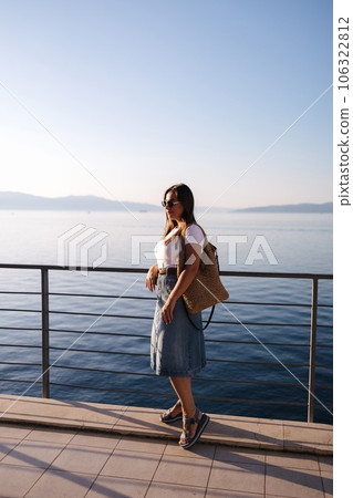 Attractive woman in denim style stand in front of sea landscape. Happy woman looking on sunset 106322812