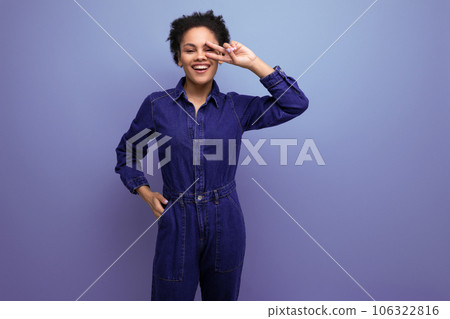 young cheerful positive brunette latin woman with afro hair gathered in a ponytail dressed in a blue 106322816