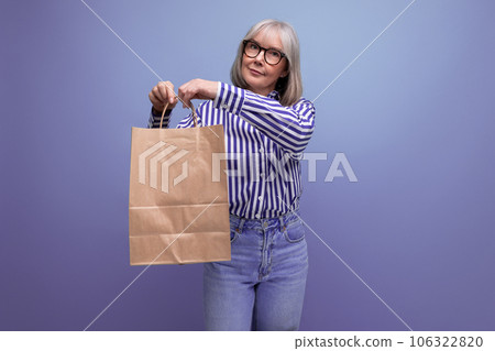 fashionable middle-aged woman with gray hair holding out a package with social assistance on a fashionable middle-aged woman with gray hair holding out a package with social assistance on a 106322820
