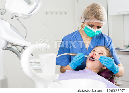 Female dentist performing treatment to girl 106322971