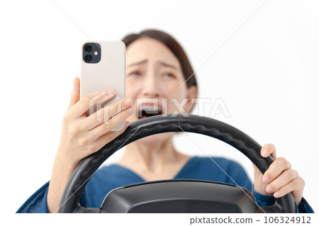 Surprised female driver looking at smartphone Surprised female driver looking at smartphone 106324912