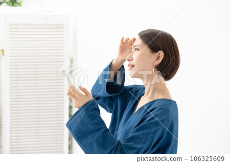 A woman who is worried about the temperature of the air conditioner A woman who is worried about the temperature of the air conditioner 106325609