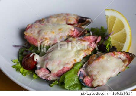 baked mussels with masago caviar and cheese on a white plate 106326834