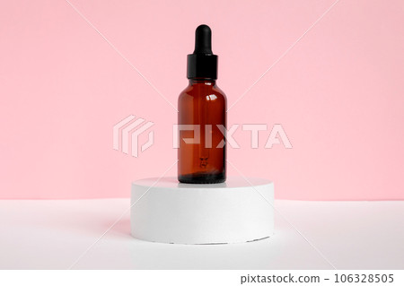 Amber glass dropper cosmetic bottles, white podium. Natural skin care SPA beauty product design. Mineral organic oil on pink background. Mock-Up. Oily pipette. Face and body treatment. Front view Amber glass dropper cosmetic bottles, white podium. Natural skin care SPA beauty product design. Mineral organic oil on pink background. Mock-Up. Oily pipette. Face and body treatment. Front view 106328505