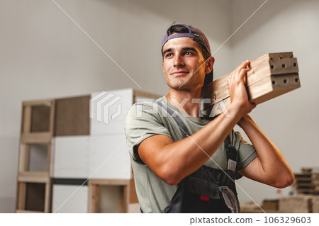 Portrait of young male carpenter standing in the wood workshop 106329603