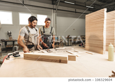 Two young men carpenters making furniture in warehouse of wood factory 106329604