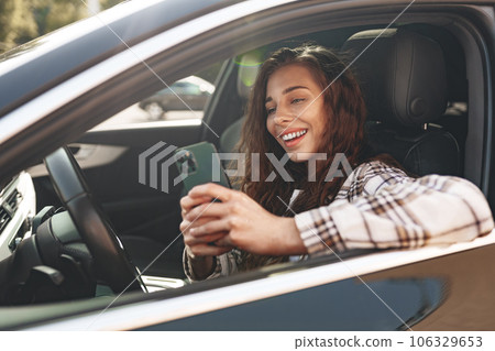 Young woman texting on her smartphone while driving a car 106329653
